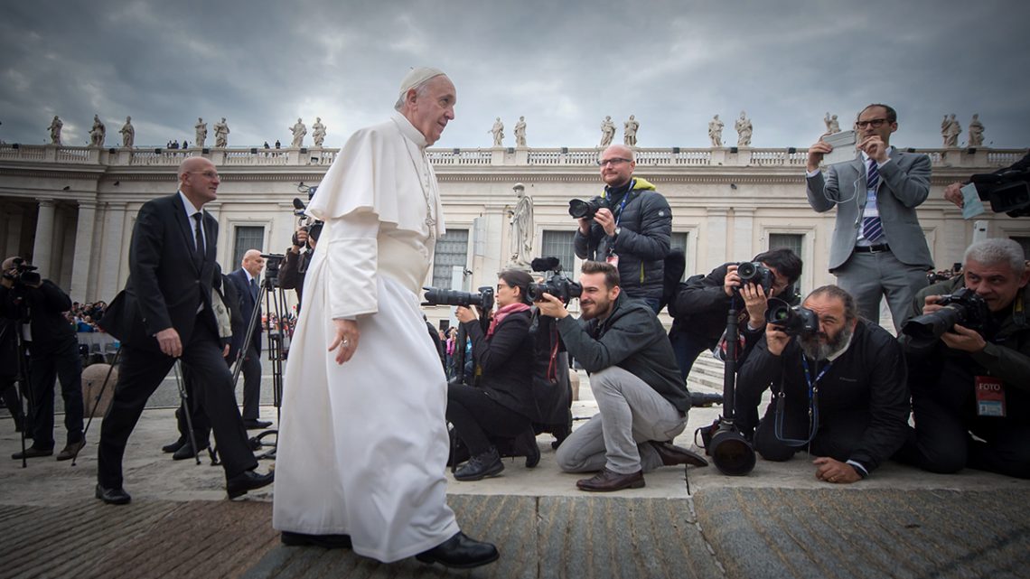 Pope Francis walking in front of cameramen