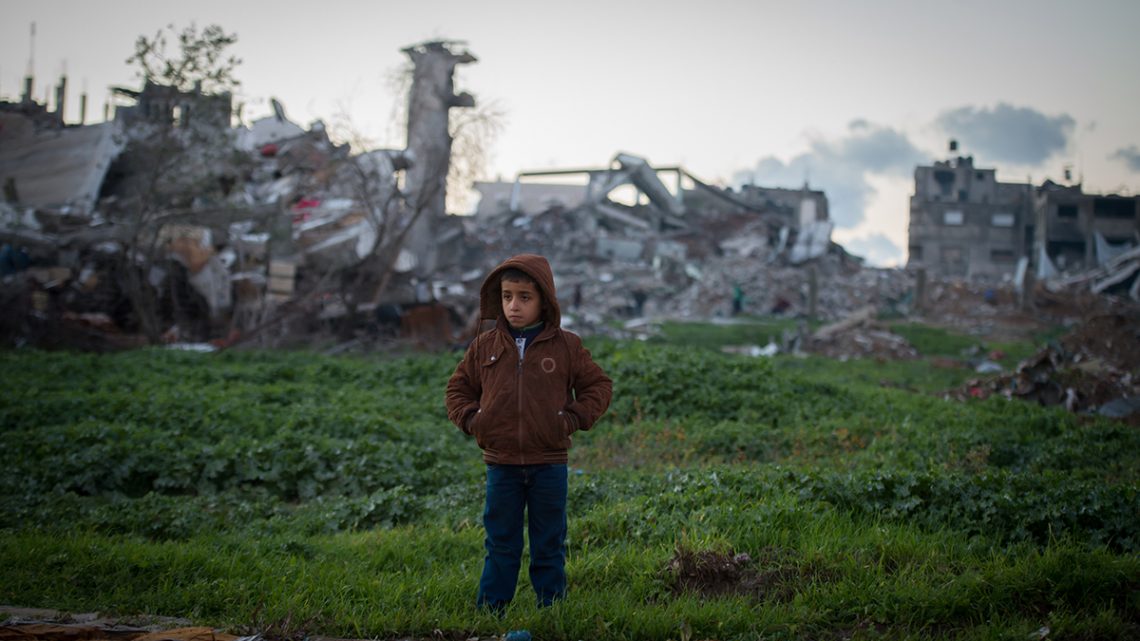 Boy in front of bombed buildings