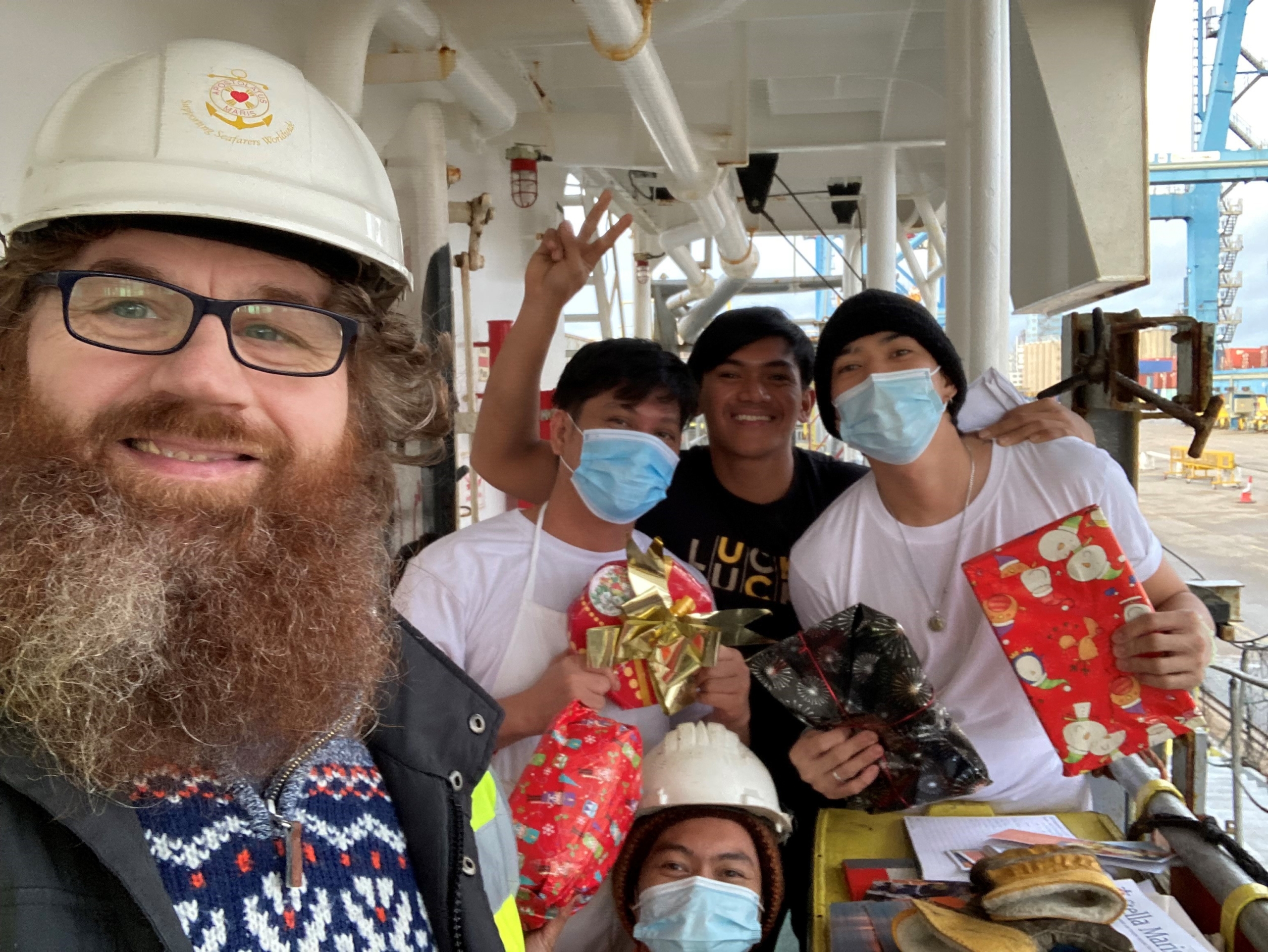 Chaplain and seafarers holding presents